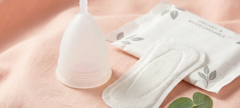 Eco-friendly sanitary pad and medical-grade silicone menstrual cup on clean background